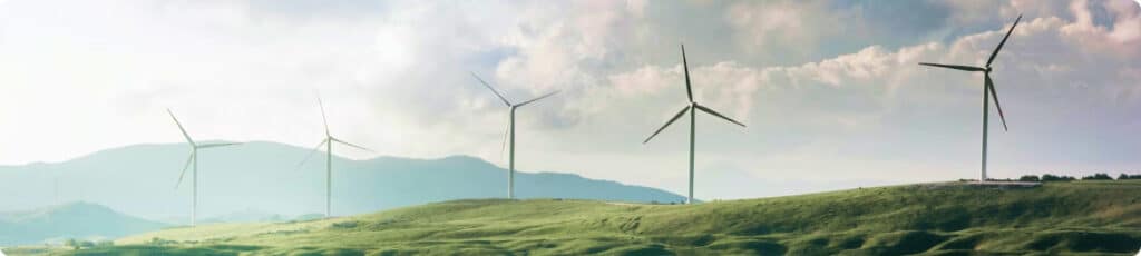five large wind turbines on a lush green mountainside